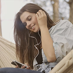Young girl, touching her ear, with ear buds in.