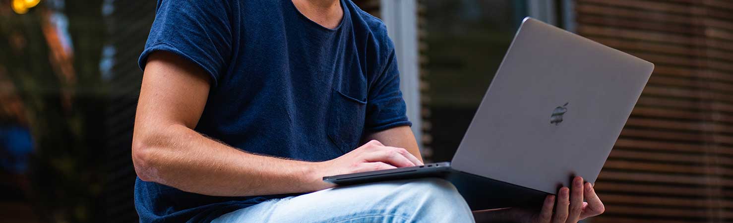A person views his laptop outside.