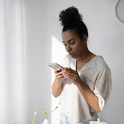 Young woman viewing her phone against a white background.
