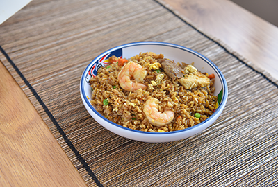 Shrimp fried rice served in a ceramic bowl on a bamboo mat
