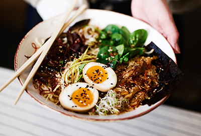Bowl of ramen with soft-boiled eggs and fresh greens