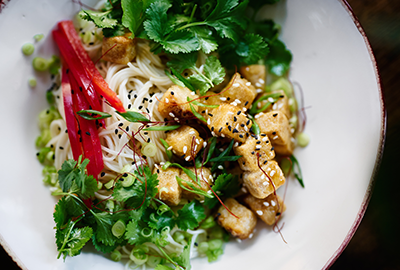 Crispy tofu and vegetables over a bed of rice noodles