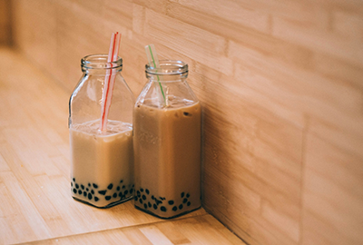 Two glass bottles of creamy milk tea with straws