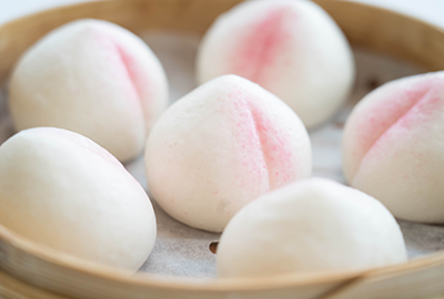 Soft peach-flavored steamed buns on a wooden plate
