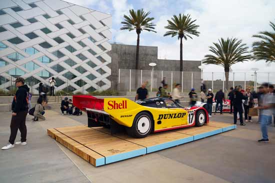 Porsche 962 on display with people gathering around it. 