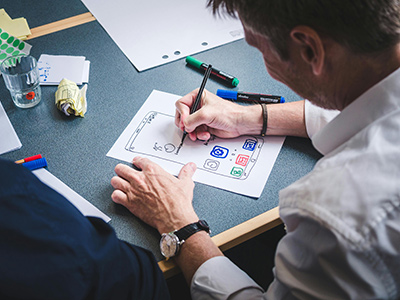 An image of a man sketching out a mobile app prototype on paper at on office desk.