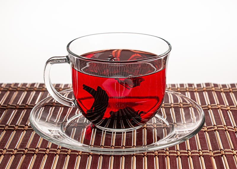 Photo of a glass cup and plate with some red tea on a red striped placemat