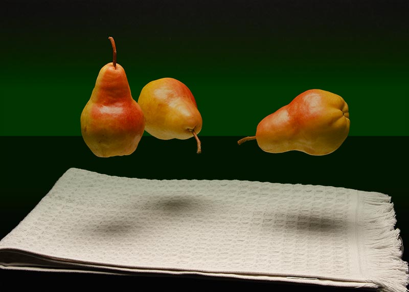 Photo of 3 floating/levitating pears over a gray folded kitchen towel