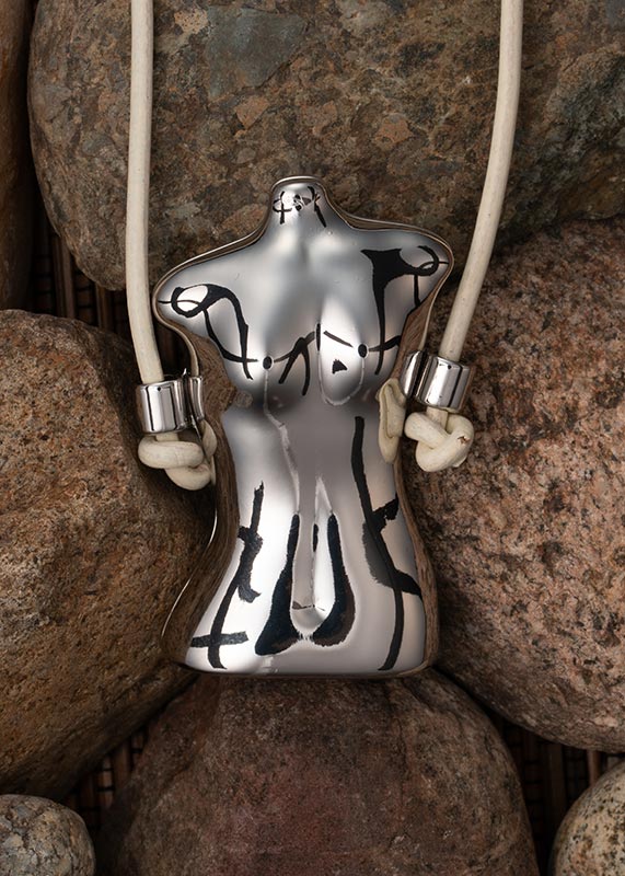 Still Photograph of a woman's torso pendant laying on rocks
