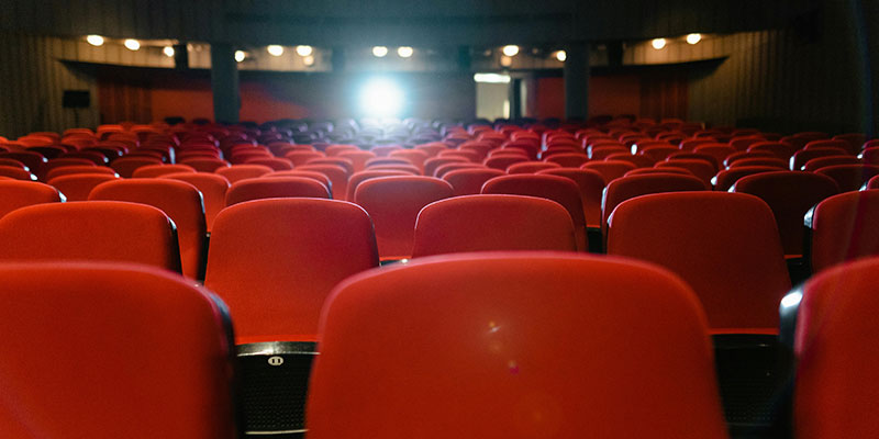 Red chairs and projector light in a theater.