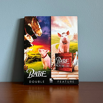 A Blu-ray slipcover featuring two different photos on each side: the left side has barnyard animals overpowering a small piglet; the right side has same piglet on top of a briefcase inbetween a goose and some mice