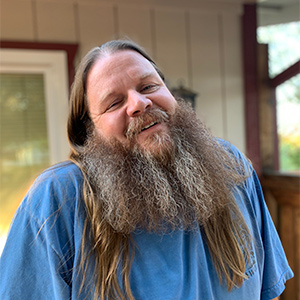Image of white male smiling with long hair and a beard