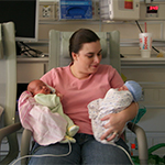 Image of mother holding twin newborn babies