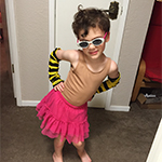 Image of child dressed in pink skirt and striped gloves with sunglasses
