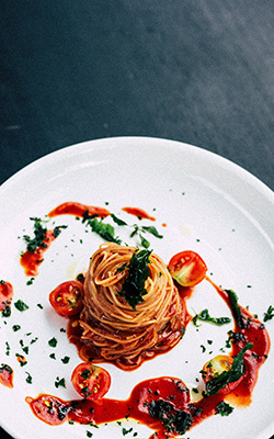 Pasta with tomato sauce and garnish on dinner plate