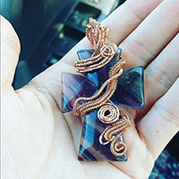picture of a purple flourite cross wirewrapped with copper wire