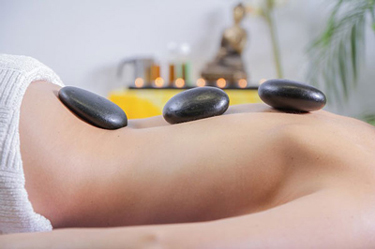 person laying down with stones on back