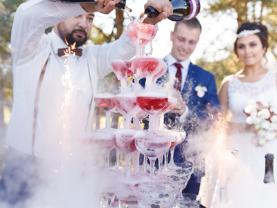 waiter pouring champagne over stacked champagne glasses