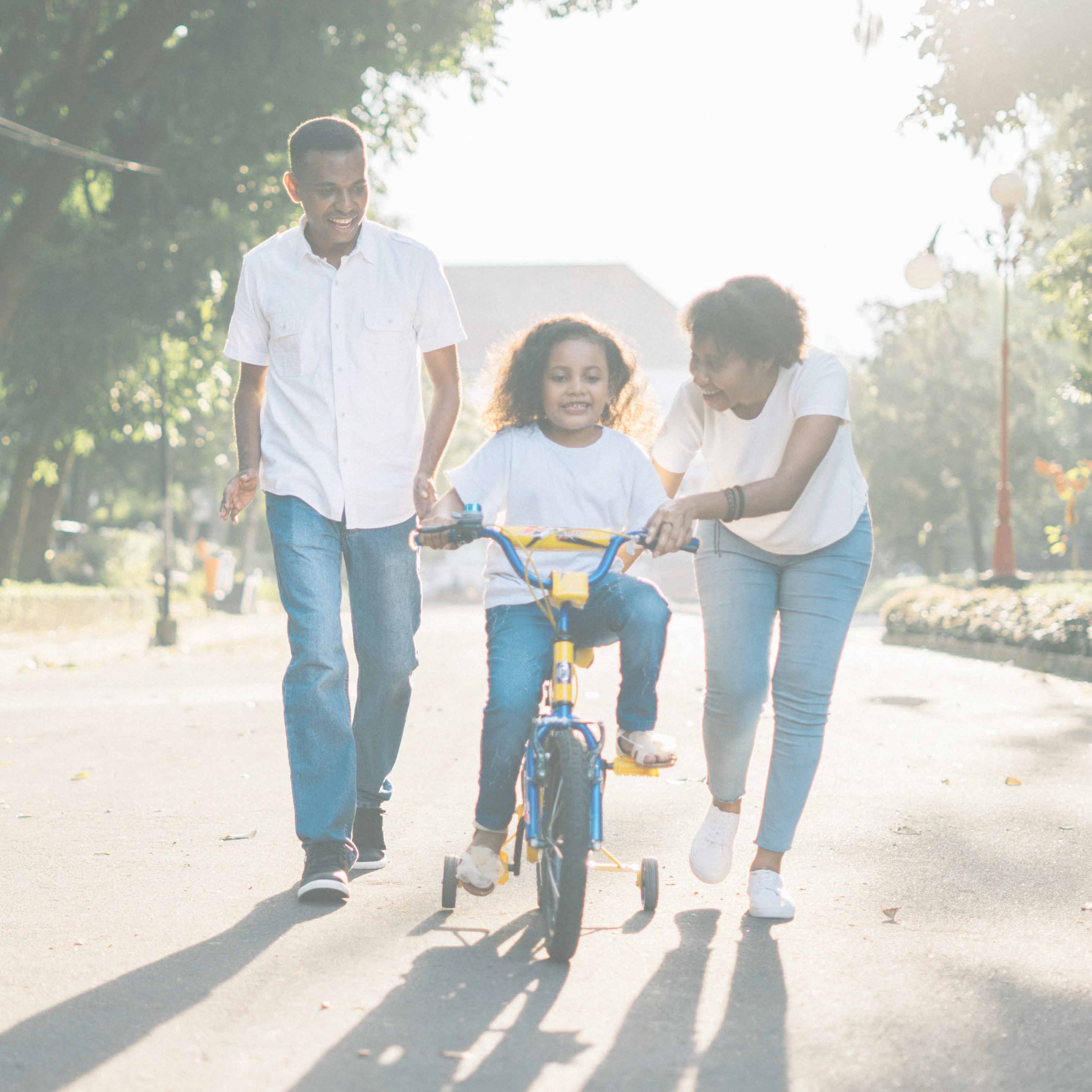 A family teaching child how to ride a bike