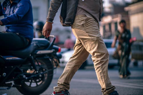 man in the front walking by focused on pants. walking through the streets.