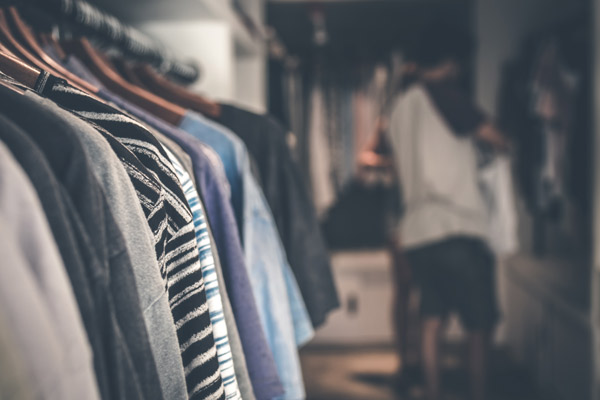 shirts on a roller to the left hand side. Focus is on shirt inside a closet and blurred background
