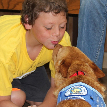 little boy giving a kiss to his service dog