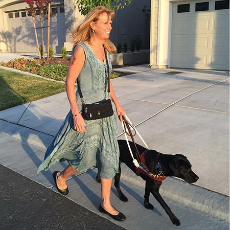 woman walking in a neigborhood with guide dog beside her